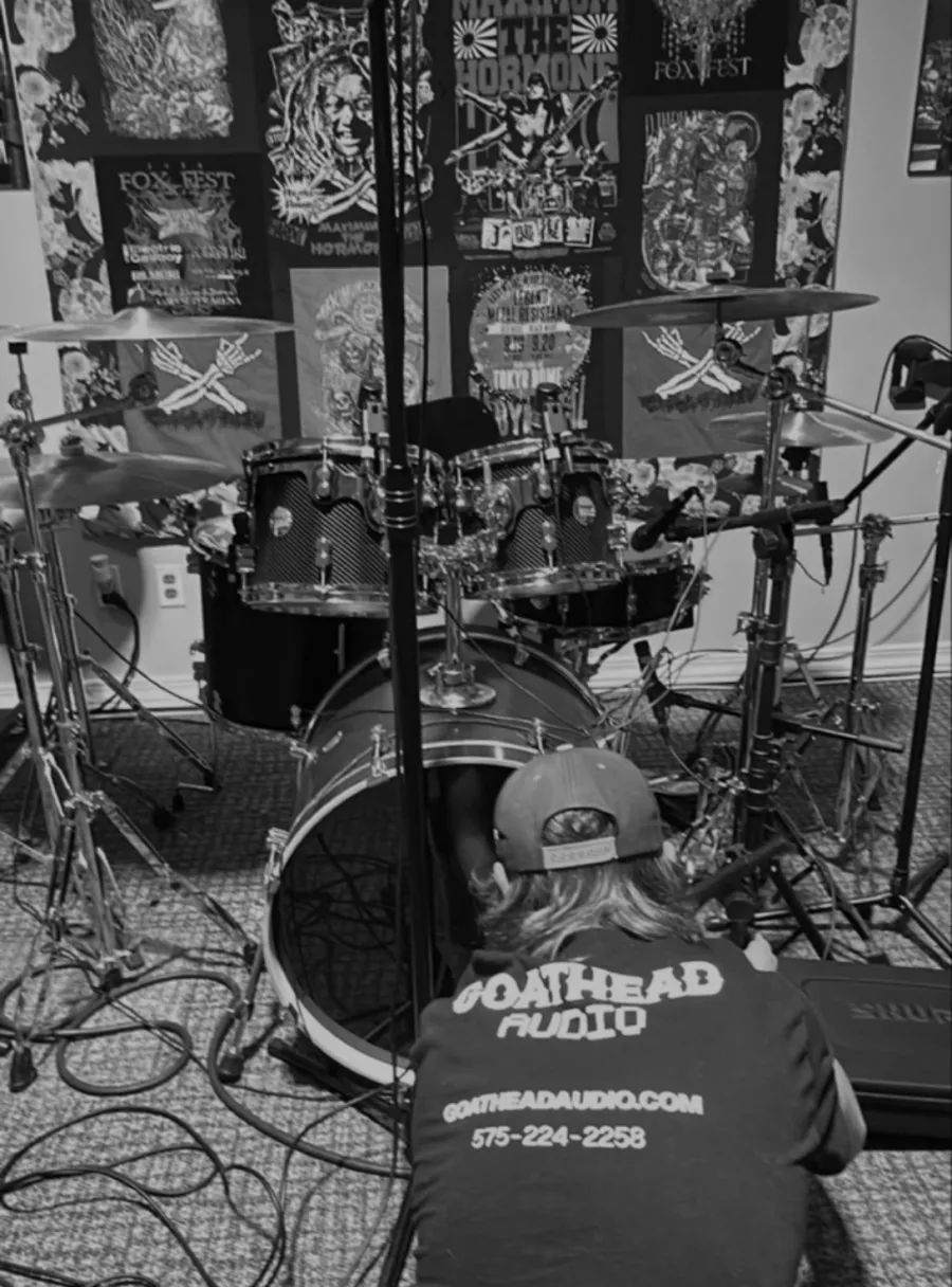 Full band tracking live in a room with drums, guitars, and engineer monitoring the session