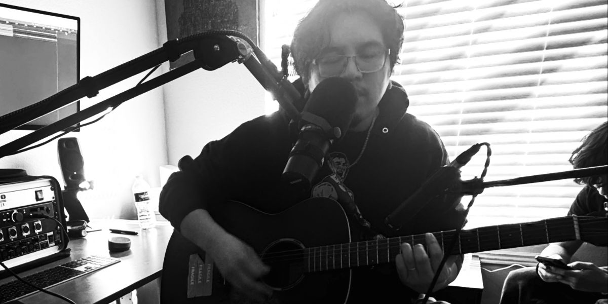 Acoustic session: person playing guitar, singing into condenser mic on boom arm. NM.